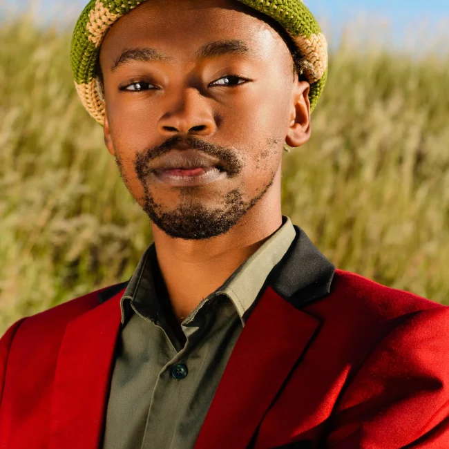 Editorial portrait shoot on young African man in a red suit standing in a field. editorial photoshoot. East London, Eastern Cape, South Africa